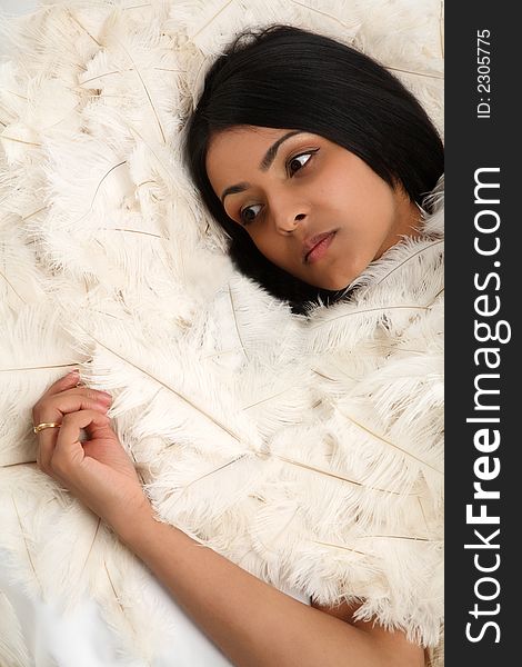 Young asian woman lying on hundreds of ostrich feathers. Young asian woman lying on hundreds of ostrich feathers