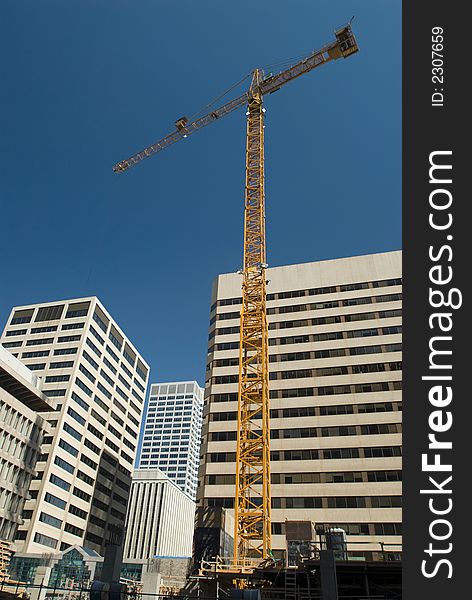 Yellow construction crane amongst office buildings. Yellow construction crane amongst office buildings