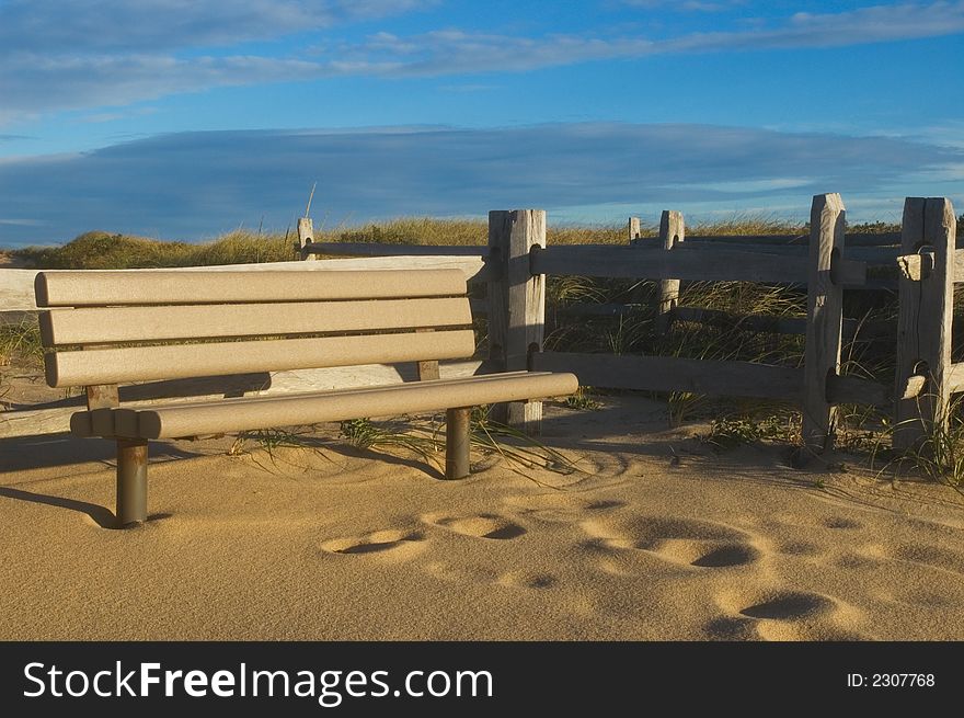 Empty park bench at sunrise in sand. Empty park bench at sunrise in sand