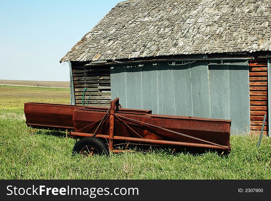 Old abandoned farm building and rusty seeding equipment. Old abandoned farm building and rusty seeding equipment.