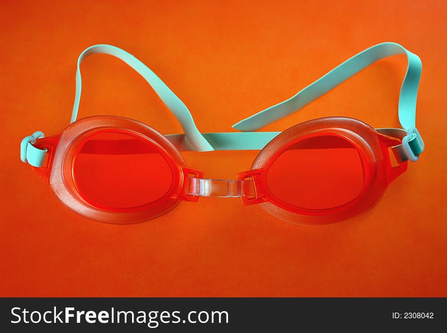 Pair of orange swimming goggles on an orange background