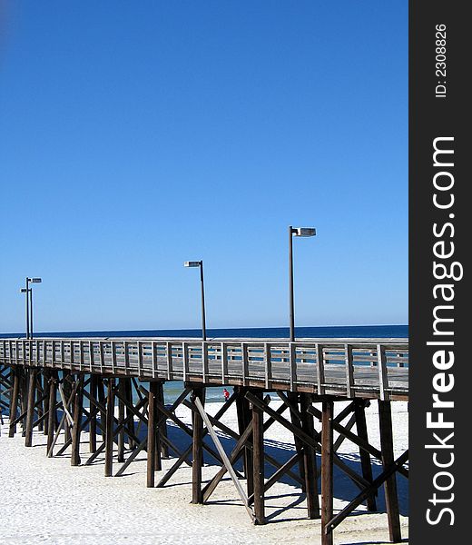 Wooden pier stretching out into the Atlantic ocean over the white sand of Florida. Wooden pier stretching out into the Atlantic ocean over the white sand of Florida