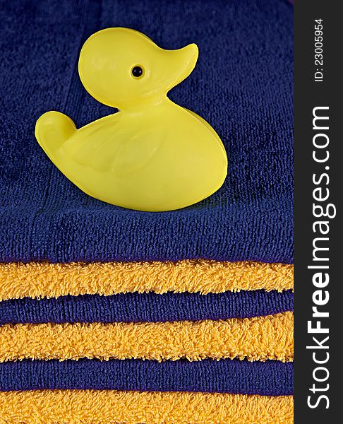 Yellow toy duck on the pile of blue and yellow towels. Yellow toy duck on the pile of blue and yellow towels