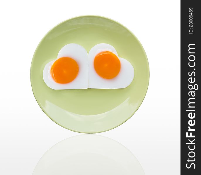 Fried egg heart on green dish on white background. Fried egg heart on green dish on white background