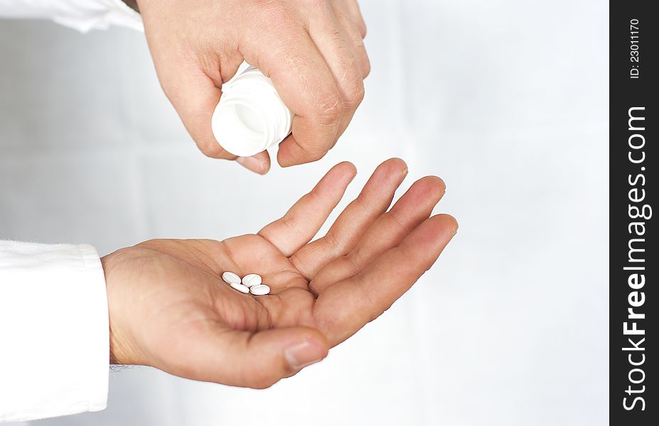 Male hand holding pills in one hand and an empty bottle in the other hand, selective focus, with space for text.