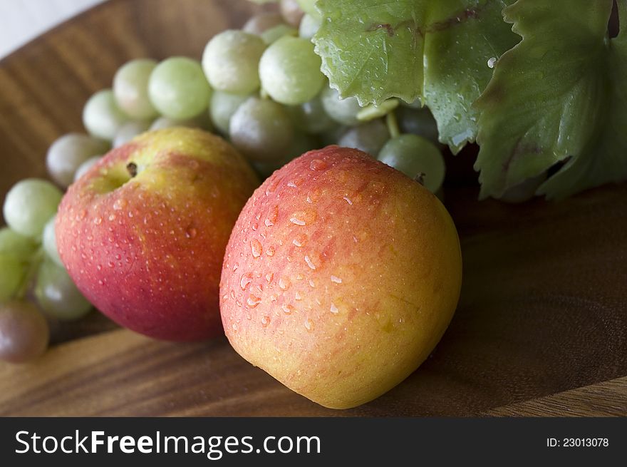 Close up fresh apples with grapes on wooden tray