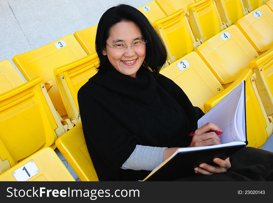 Young Asian college student with smiling sitting on grandstand to present education concept. Young Asian college student with smiling sitting on grandstand to present education concept