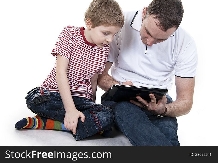 Father and son sitting on a floor with the computer on white isolation. Father and son sitting on a floor with the computer on white isolation