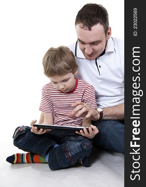 Father and son sitting on a floor with the computer on white isolation. Father and son sitting on a floor with the computer on white isolation