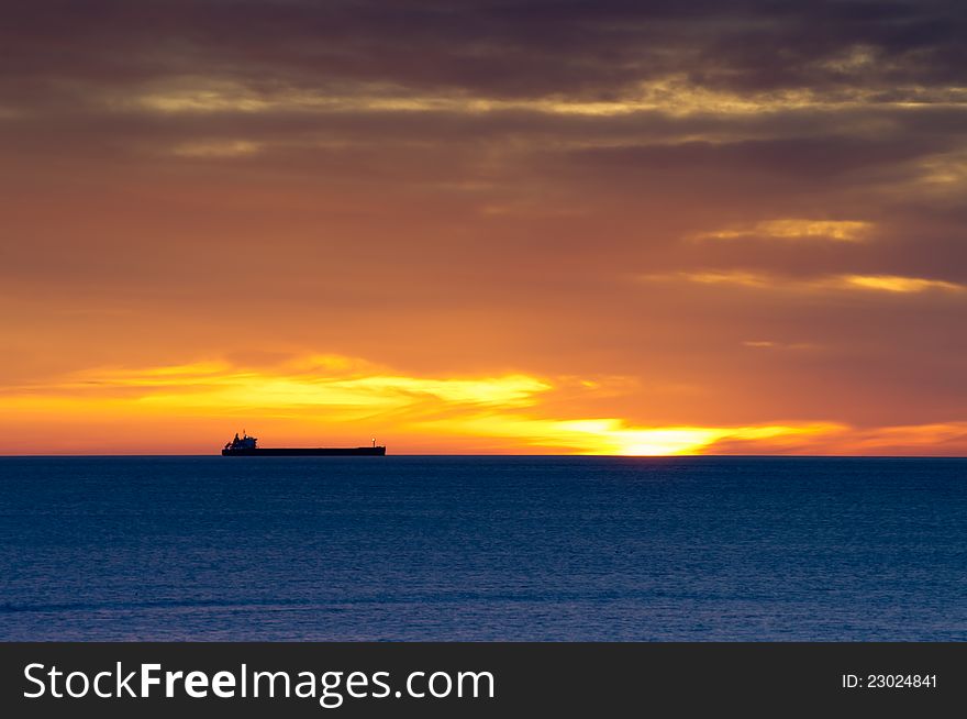 Cargo Ship On Horizon At Dawn