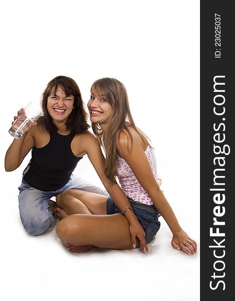 Two cheerful girls hold a glass with water