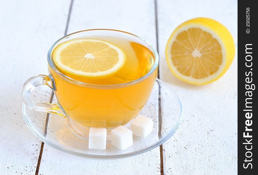 Tea with lemon in a transparent cup on a white table