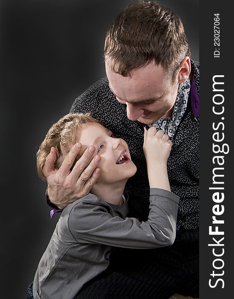 Father and son cheerfully talk. On a gray background. Boy not in focus.