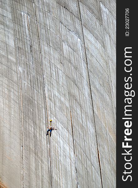 The woman is bungee jumping along the concrete wall. The Contra Dam is a popular bungee jumping venue in the Swiss Alps. The woman is bungee jumping along the concrete wall. The Contra Dam is a popular bungee jumping venue in the Swiss Alps.