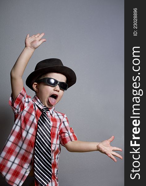 The boy in a hat and black glasses on a gray background