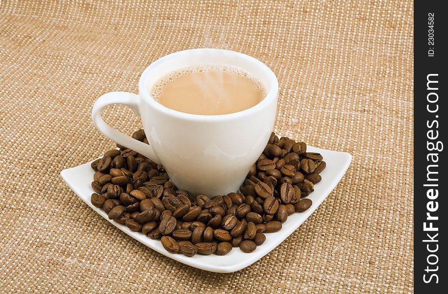 Coffee and milk and saucer with grains on a background sacking