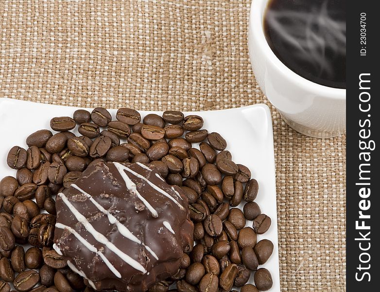 Coffee black,biscuits and grains of lie on a saucer on a background sacking. Coffee black,biscuits and grains of lie on a saucer on a background sacking