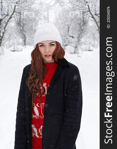 Portrait of beautiful young red hair woman outdoors in winter looking at camera and enjoying snow