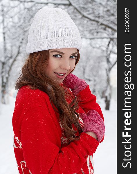 Portrait of beautiful young red hair woman outdoors in winter looking at camera and enjoying snow