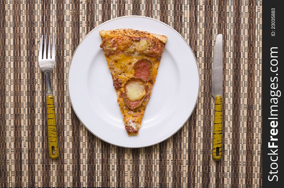 A slice of pizza on white plate with fork and knife, good for your articles