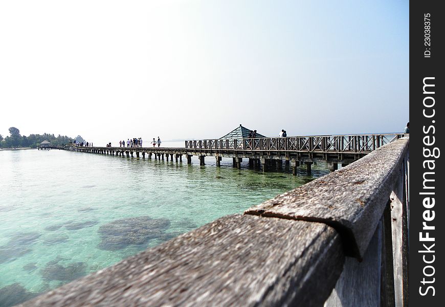 A little wooden bridge connecting two small islands over the sea. A little wooden bridge connecting two small islands over the sea