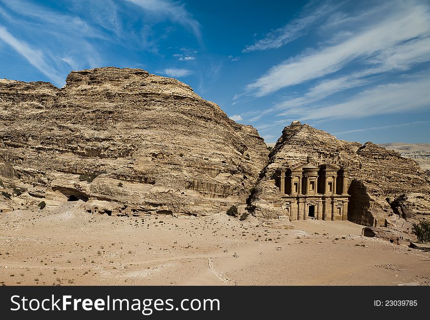 The Monastery (al-Deir or ad-Dayr in Arabic), a Nabatean structure from the 1st century BC, dominates the crest of a mountain north of Petraâ€™s city center. Even at 50 meters in height and 45 meters width, it is dwarfed by its sandstone backdrop. The flat plaza facing the monument was carved from rock. Two visitors make their way along a path leading to a promontory and viewpoint with a 360-degre. The Monastery (al-Deir or ad-Dayr in Arabic), a Nabatean structure from the 1st century BC, dominates the crest of a mountain north of Petraâ€™s city center. Even at 50 meters in height and 45 meters width, it is dwarfed by its sandstone backdrop. The flat plaza facing the monument was carved from rock. Two visitors make their way along a path leading to a promontory and viewpoint with a 360-degre