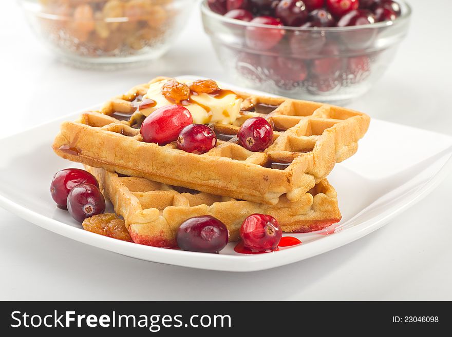 A plate of waffles with fresh fruits and honey