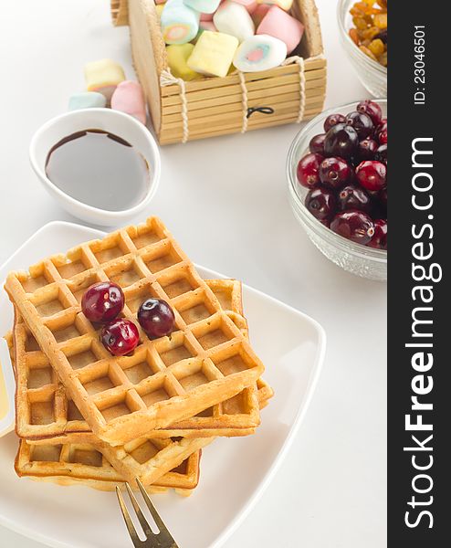 A plate of waffles with fresh fruits and butter