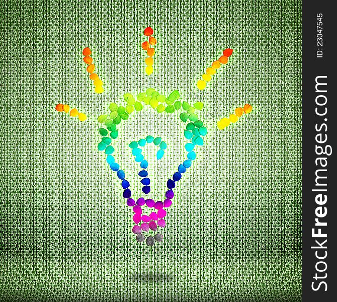 Idea template. Multi-colored light bulb from seeds on a green background