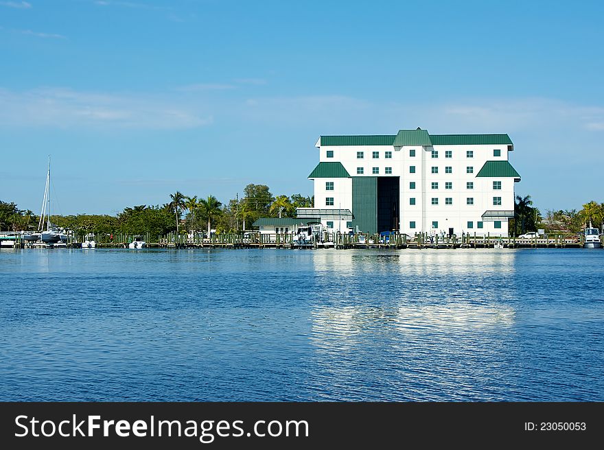 A large white boathouse with door open overlooks bay in florida. A large white boathouse with door open overlooks bay in florida.