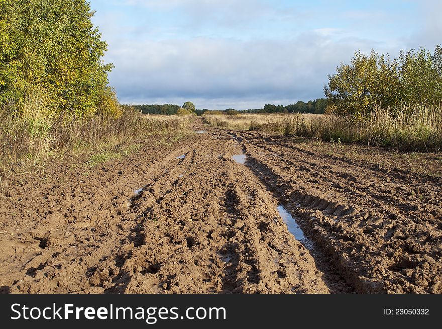 Country dirt road after the rain, the clouds on the horizon