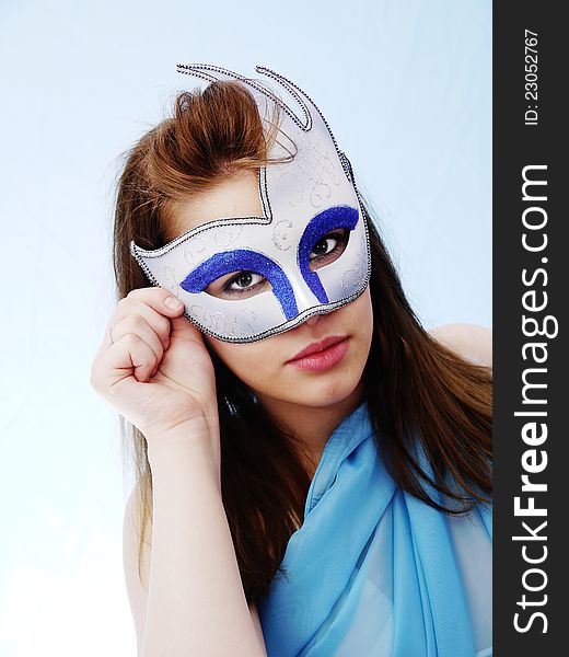 Masquerade Mask on pretty brunette. Soft Blue costume and background. Masquerade Mask on pretty brunette. Soft Blue costume and background
