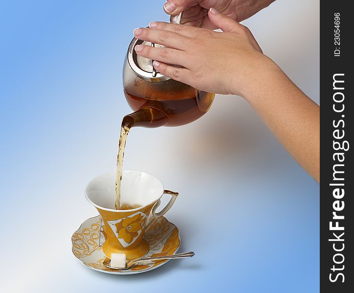 Tea being poured into glass tea cup on a white background.