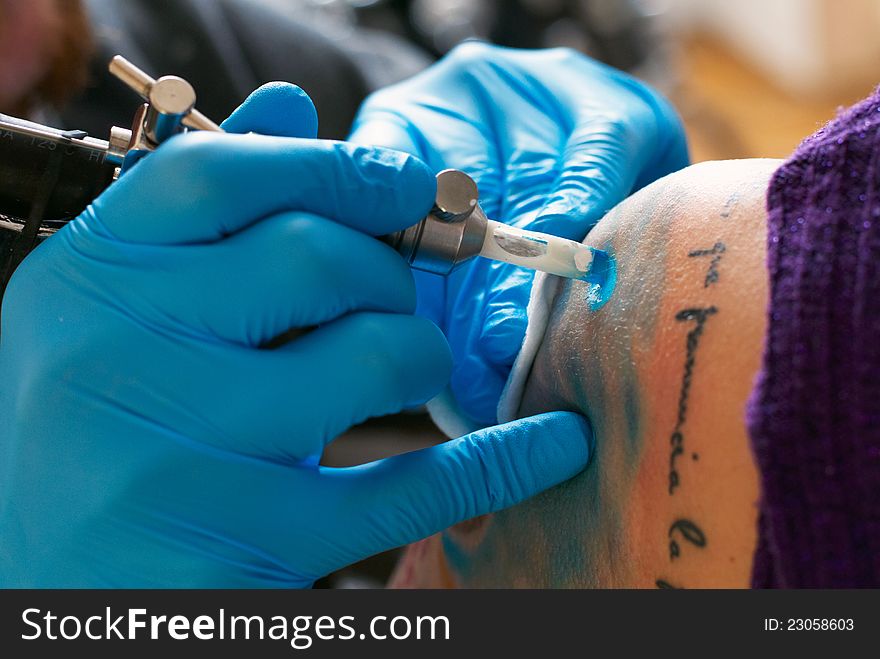 Hands of tattooist create a tattoo on a woman's shoulder, close up