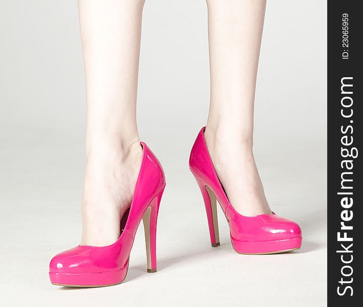 Close Up of Woman's Bare Legs in Pink High Heels Standing Against a White Background. Close Up of Woman's Bare Legs in Pink High Heels Standing Against a White Background