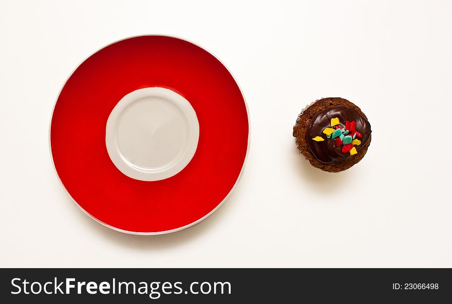 Brown delicious muffin on red plate  on white background. Brown delicious muffin on red plate  on white background