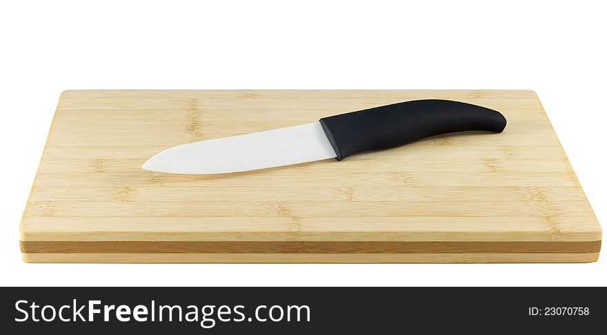 Ceramic Knife on a chopping board isolated on white. Ceramic knives will not corrode in harsh environments, are non-magnetic, and do not conduct electricity. Their resistance to strong acid and caustic substances, and their ability to retain a cutting edge longer than forged metal knives, make them a suitable culinary tool for slicing boneless meat, vegetables and fruit.