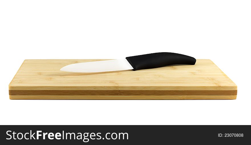 Ceramic Knife on a chopping board isolated on white. Ceramic knives will not corrode in harsh environments, are non-magnetic, and do not conduct electricity. Their resistance to strong acid and caustic substances, and their ability to retain a cutting edge longer than forged metal knives, make them a suitable culinary tool for slicing boneless meat, vegetables and fruit.