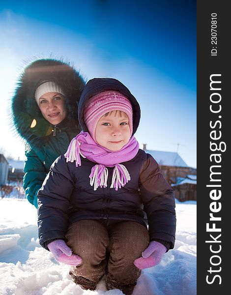 Mother and girl playing in snow outdor.