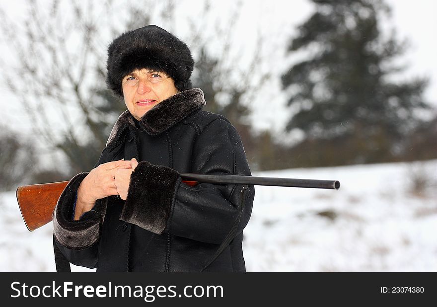 A female hunter with a shotgun in a forest during winter season. A female hunter with a shotgun in a forest during winter season