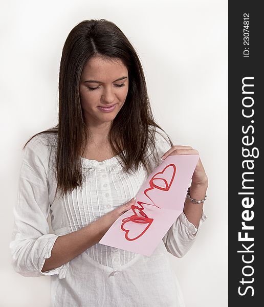 Young girl photographed on white background with card with pop up hearts for the  Valentines day. Young girl photographed on white background with card with pop up hearts for the  Valentines day