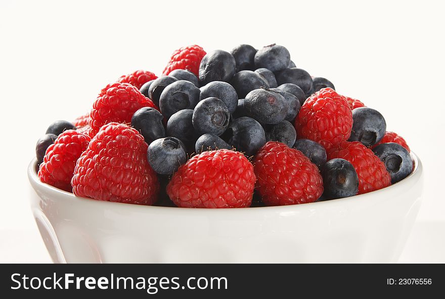 Bowl of blueberries and raspberries photographed on white background. Bowl of blueberries and raspberries photographed on white background