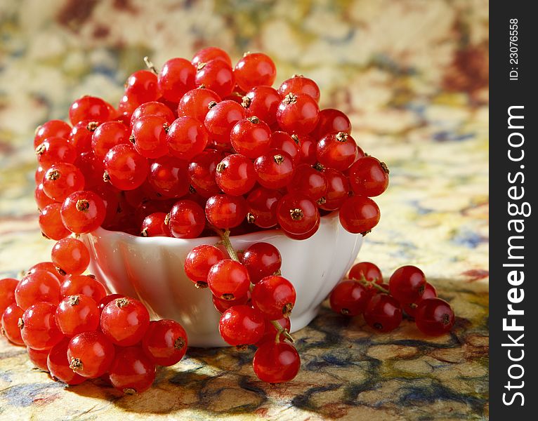 Fresh red currants photographed in small bowl on colorful background