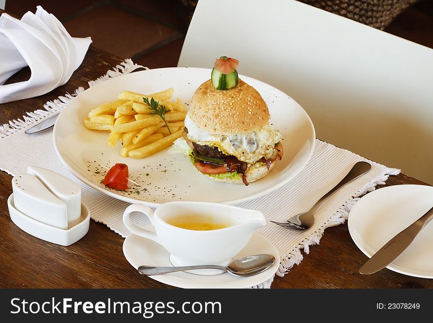 Gourmet egg hamburger and chips on a white plate in a restaurant setting