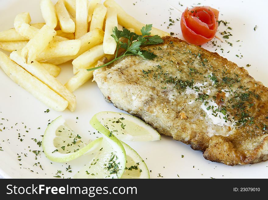 Gourmet restaurant hake fish and chips on a white garnished plate. Gourmet restaurant hake fish and chips on a white garnished plate