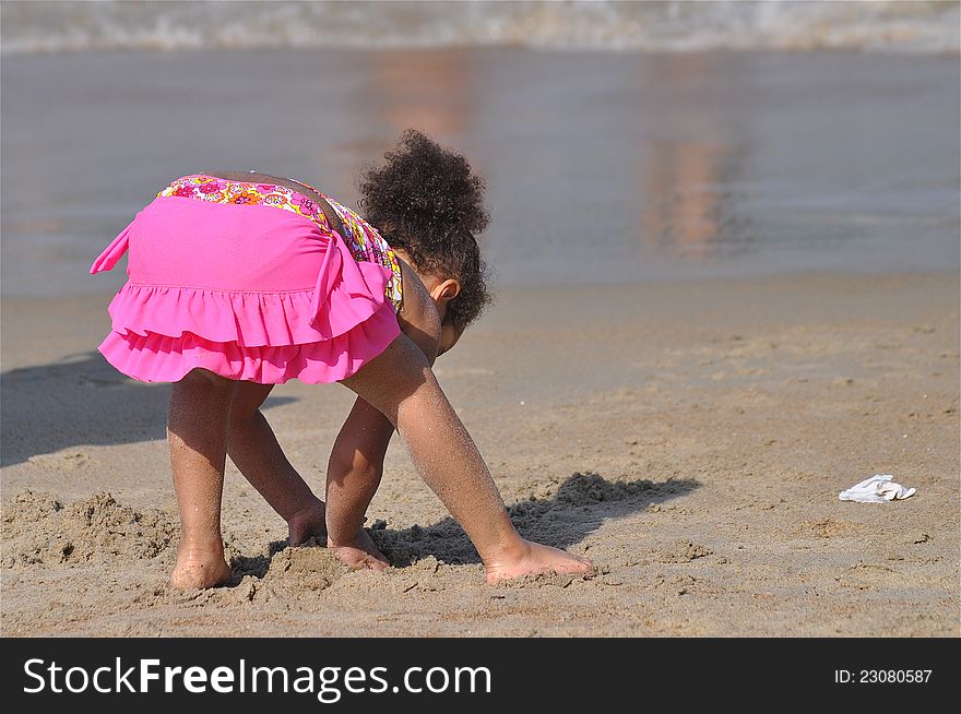 A curious little girl is at a beach shore looking for shells. A curious little girl is at a beach shore looking for shells.