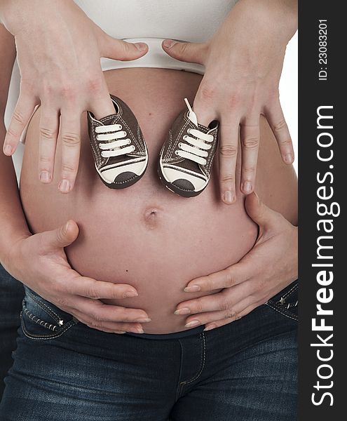 Pregnant woman holding her belly and boots. Pregnant woman holding her belly and boots