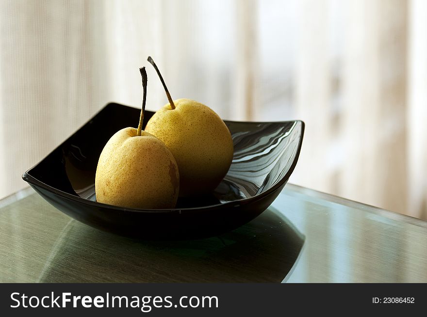 Two yellow pears on a black plate. Two yellow pears on a black plate