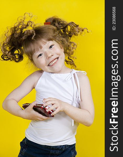 Little girl playing handheld portable game console. Yellow background. Little girl playing handheld portable game console. Yellow background