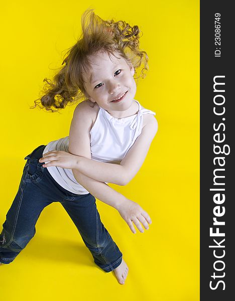 Cheerful girl dances on a yellow background. Cheerful girl dances on a yellow background